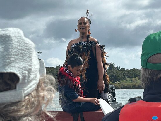 A woman sharing a cultural experience aboard a waka with visitors in the Bay of Islands