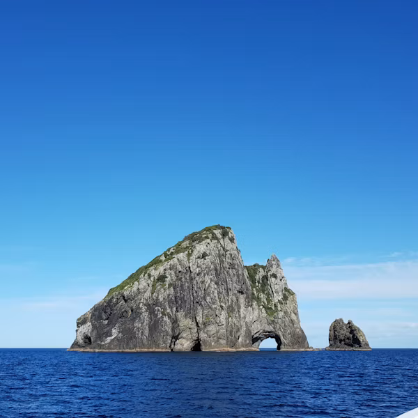 The Hole in the Rock surrounded by deep blue sea beneath a clear blue sky